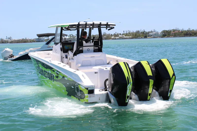 Slide: The Image of 2024 Fountain 32 NX boat with triple engines cruising on clear blue water. - 4
