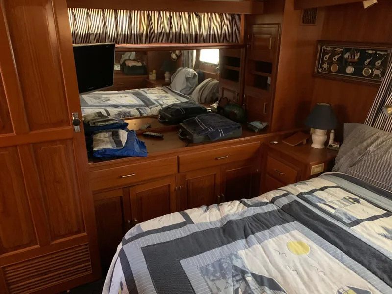 Slide: The Image of 1987 Kha Shing Vista 40 yacht bedroom with wooden cabinetry and nautical-themed bedding. - 17