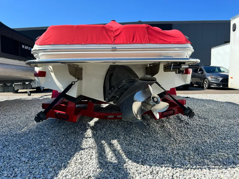 Slide: The Image of 2009 Cobalt 222 boat with red cover, rear view, on gravel lot. - 13