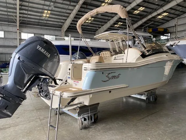 The Image of 2024 Scout 215 Dorado boat with Yamaha engine in a warehouse setting. - 0