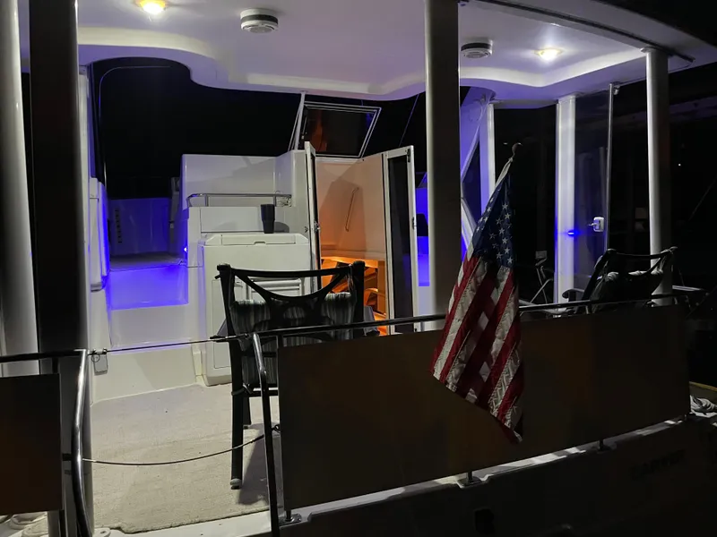 Slide: The Image of 1996 Carver 370 Aft Cabin yacht with illuminated deck and American flag at night. - 24