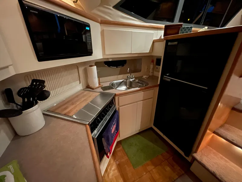 Slide: The Image of 1996 Carver 370 Aft Cabin kitchen with sink, stove, microwave, and refrigerator. - 31