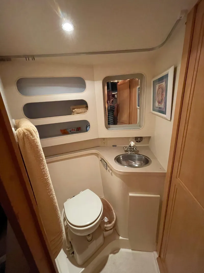 Slide: The Image of 1996 Carver 370 Aft Cabin bathroom with toilet, sink, and storage shelves. - 33