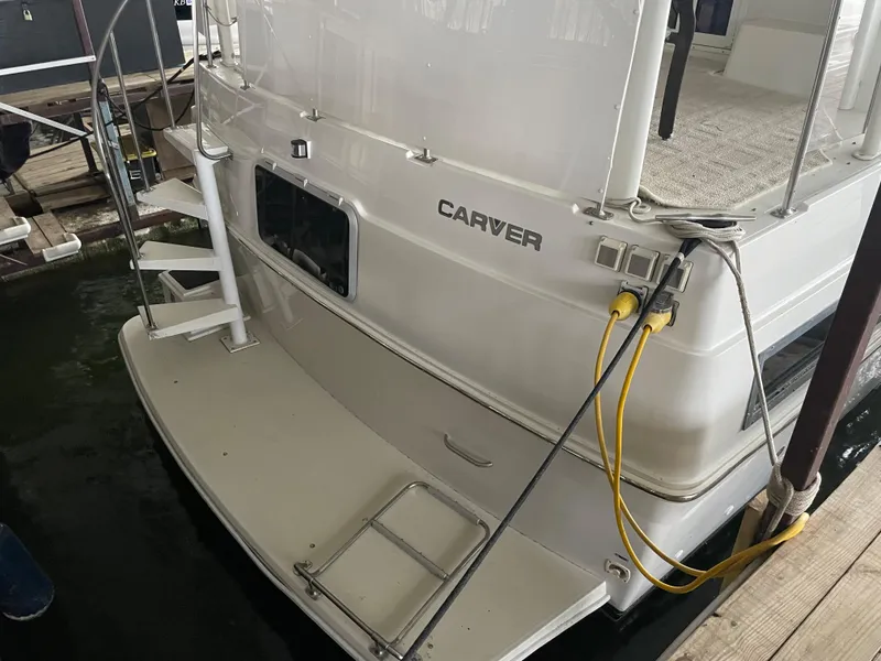 Slide: The Image of 1996 Carver 370 Aft Cabin boat docked, showing rear deck and ladder. - 5