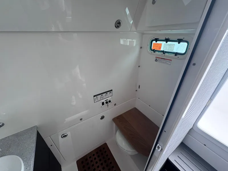 Slide: The Image of 2024 Everglades 395 CC boat interior bathroom with window and wooden seat. - 19