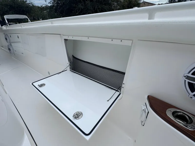 Slide: The Image of 2024 Everglades 395 CC boat storage compartment with open hatch and netting. - 33