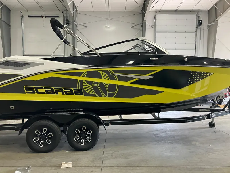 Slide: The Image of 2024 Scarab 285 boat in a showroom, black and yellow design, on a trailer. - 1