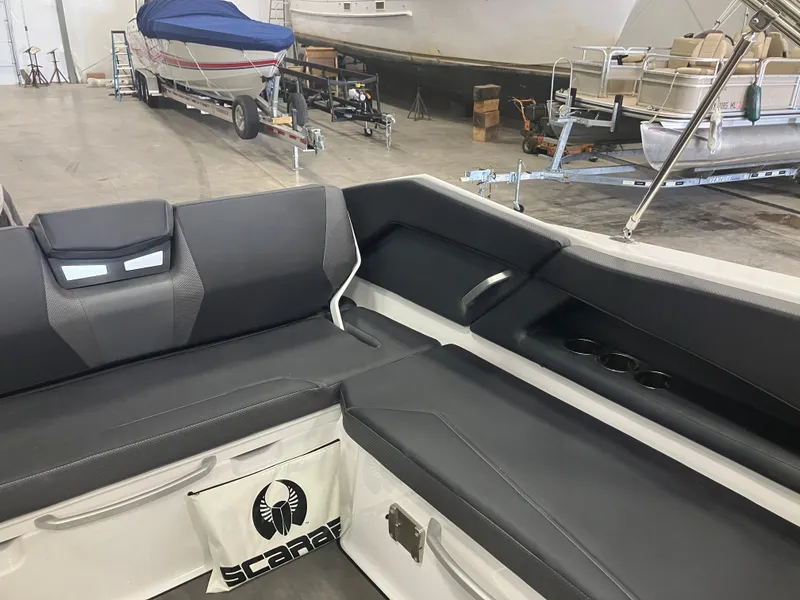 Slide: The Image of 2024 Scarab 285 boat interior seating with black cushions and built-in cup holders. - 11