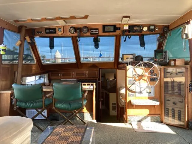 Slide: The Image of 1977 Tollycraft 48' Cockpit Motor Yacht interior with helm, green chairs, and nautical instruments. - 3