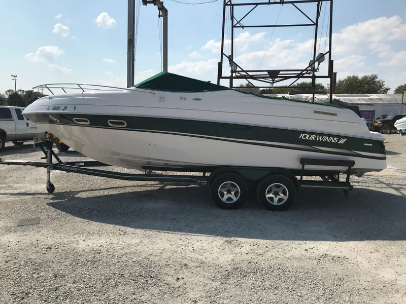 The Image of 2002 Four Winns 245 Sundowner boat on a trailer in a parking lot. - 1