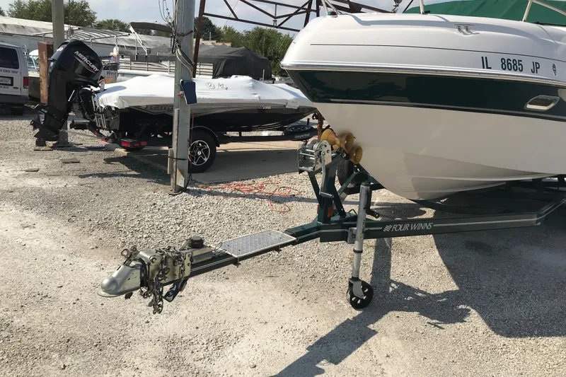 Slide: The Image of 2002 Four Winns 245 Sundowner boat on a trailer in a gravel lot. - 22