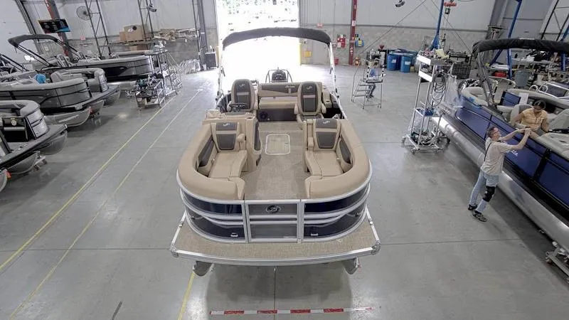 Slide: The Image of 2024 Barletta C22UC pontoon boat in a manufacturing facility, showcasing spacious seating. - 18