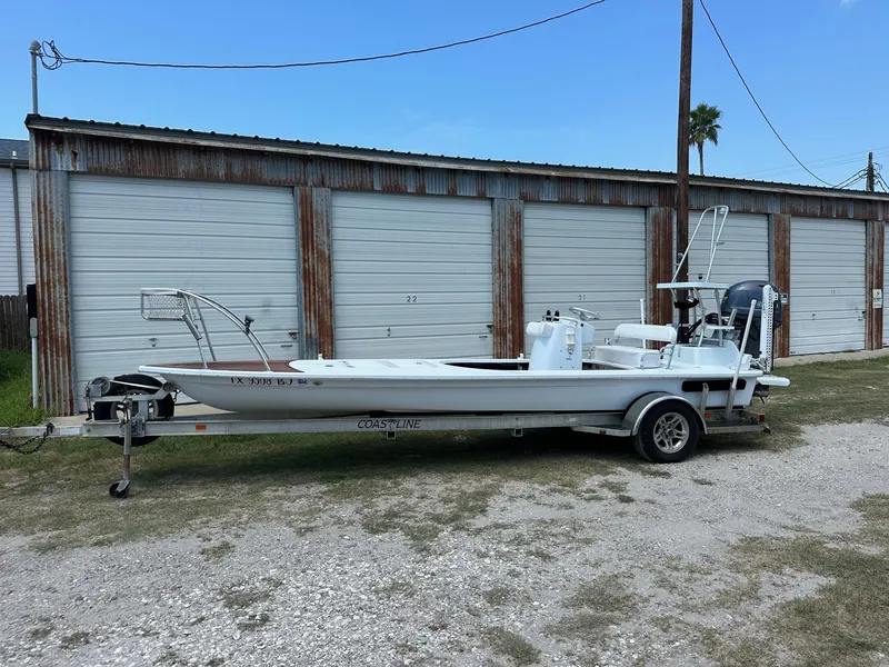 Slide: The Image of White 2011 NewWater Stilt boat on trailer, parked in front of storage units. - 1