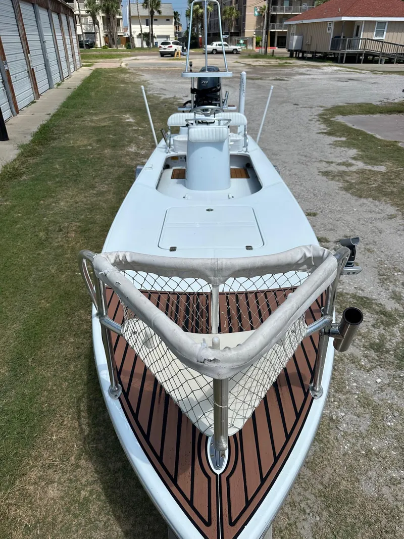 Slide: The Image of 2011 NewWater Stilt boat with wooden deck and netted bow, parked outdoors. - 2