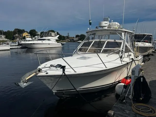 Slide: The Image of 2003 Carolina Classic 28 boat docked at a marina, surrounded by other vessels. - 2