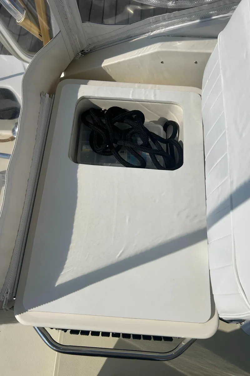 Slide: The Image of 2003 Carolina Classic 28 boat seat with storage compartment, containing coiled ropes. - 20
