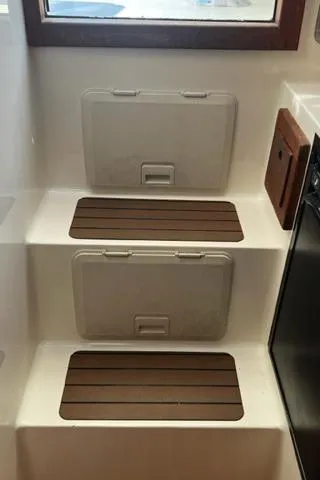 Slide: The Image of 2003 Carolina Classic 28 boat interior steps with storage compartments and wooden accents. - 22