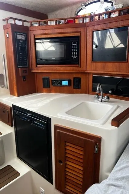 Slide: The Image of 2003 Carolina Classic 28 boat interior with kitchenette, featuring microwave, sink, and storage cabinets. - 23