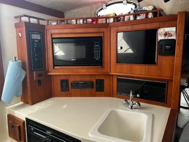 Slide: The Image of 2003 Carolina Classic 28 boat kitchen with microwave, sink, and wooden cabinetry. - 24