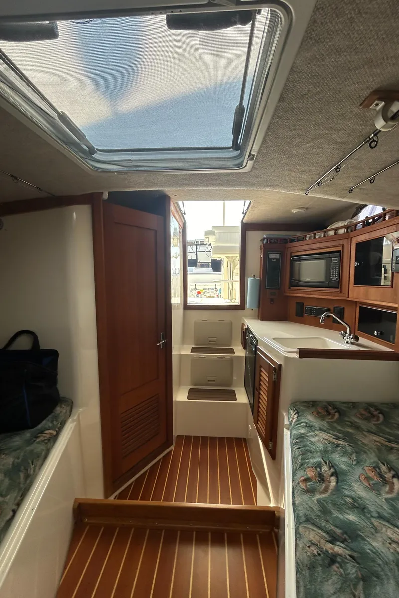 Slide: The Image of Interior of a 2003 Carolina Classic 28 boat, featuring wood accents and compact kitchen area. - 29