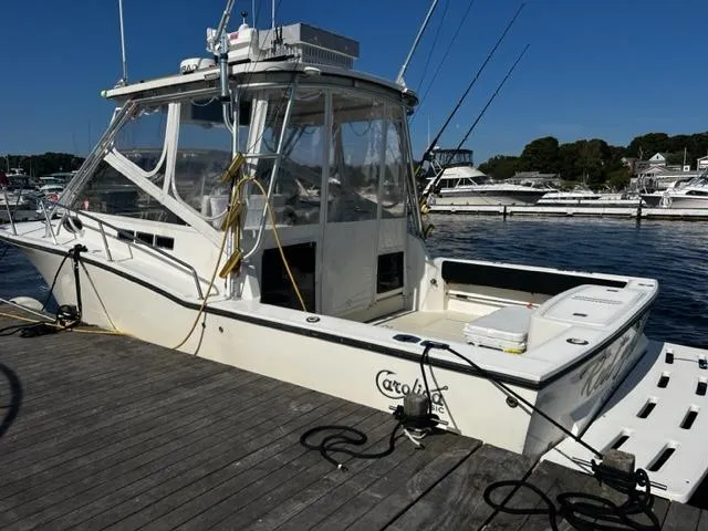 Slide: The Image of 2003 Carolina Classic 28 boat docked at marina, featuring fishing rods and clear skies. - 3