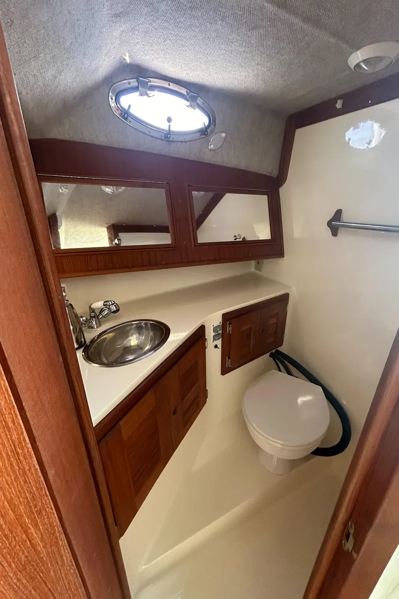 Slide: The Image of 2003 Carolina Classic 28 boat bathroom with sink, toilet, and wooden cabinetry. - 31