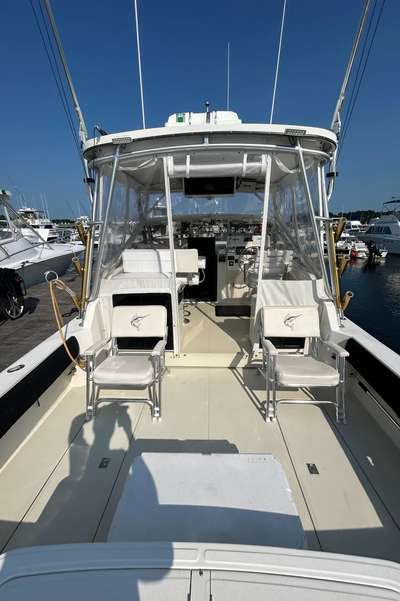 Slide: The Image of 2003 Carolina Classic 28 boat with fishing chairs and clear canopy, docked at marina. - 8