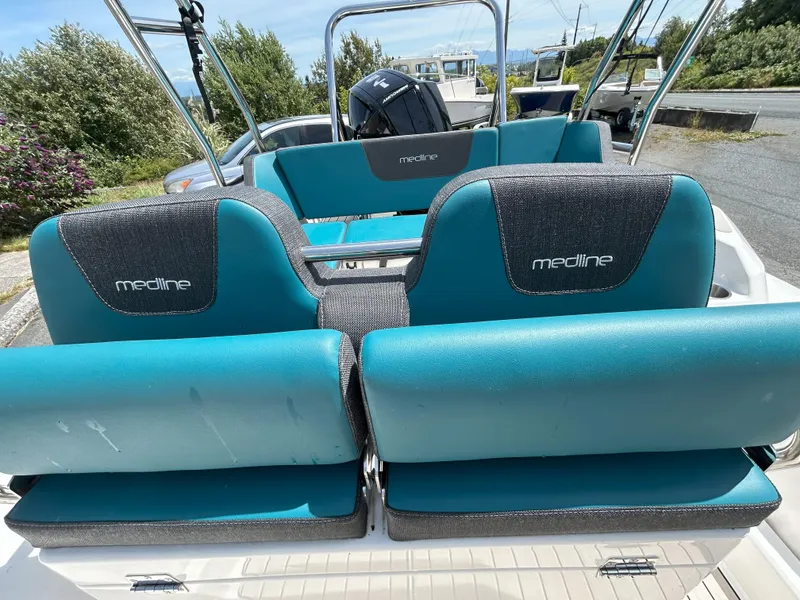 Slide: The Image of 2024 Zodiac Medline 6.8 boat seats with teal and gray upholstery, parked outdoors. - 12