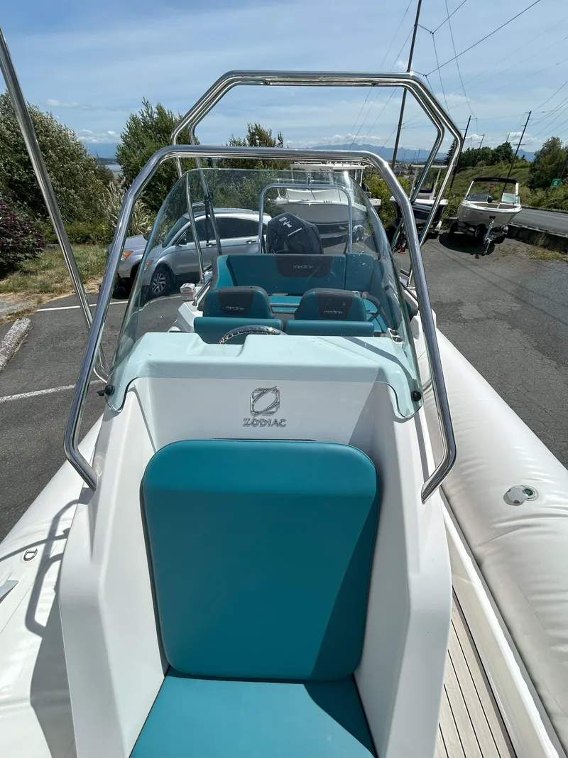 Slide: The Image of 2024 Zodiac Medline 6.8 boat with teal seating and windshield, parked outdoors. - 5