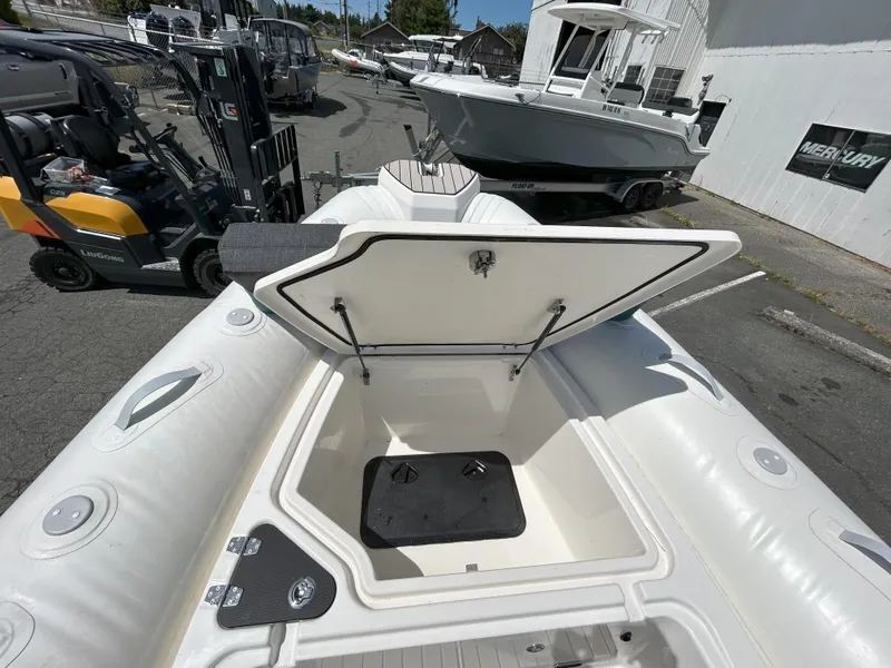 Slide: The Image of 2024 Zodiac Medline 6.8 boat with open storage compartment, docked outdoors. - 8