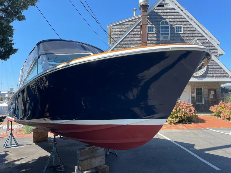 The Image of 2005 Hunt Yachts Harrier 25 boat on stands near a shingled building. - 0