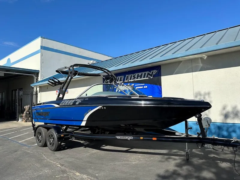 Slide: The Image of 2024 Sanger V215 SX boat on trailer, blue and black, parked outside. - 1