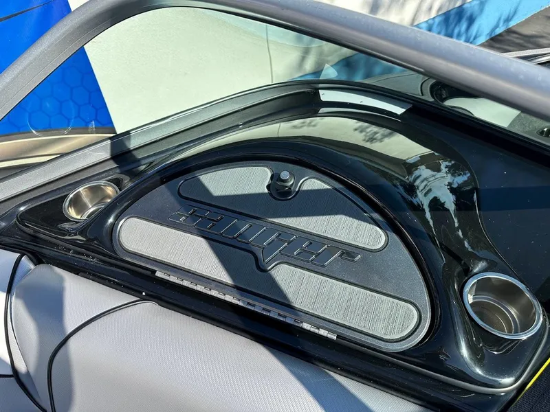Slide: The Image of 2024 Sanger V215 SX boat dashboard with cup holders and logo. - 19