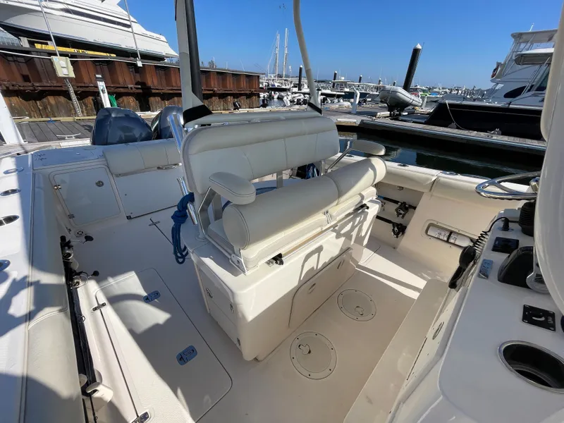 Slide: The Image of 2011 Pursuit 280 Center Console boat interior at marina, featuring seating and storage. - 21