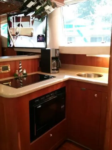 Slide: The Image of 2000 Cruisers Yachts 4450 Express Motoryacht kitchen with modern appliances and wooden cabinetry. - 18
