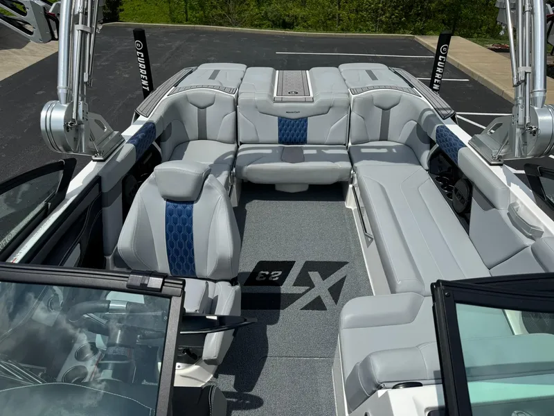 Slide: The Image of 2023 MasterCraft XT23 boat interior with gray and blue seating, open layout, and modern design. - 12