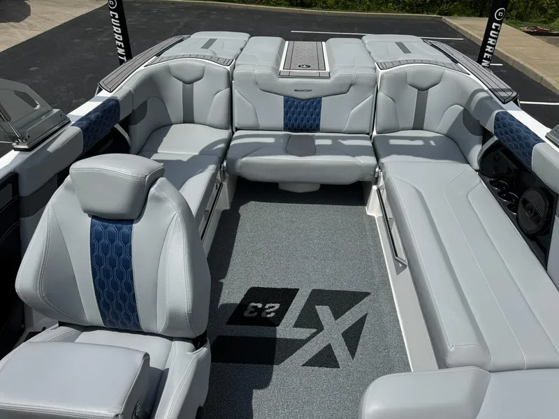Slide: The Image of 2023 MasterCraft XT23 boat interior with gray and blue seating, featuring modern design and spacious layout. - 13