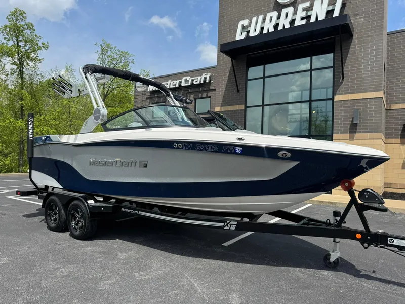 Slide: The Image of 2023 MasterCraft XT23 boat on trailer outside dealership, showcasing sleek design and modern features. - 4