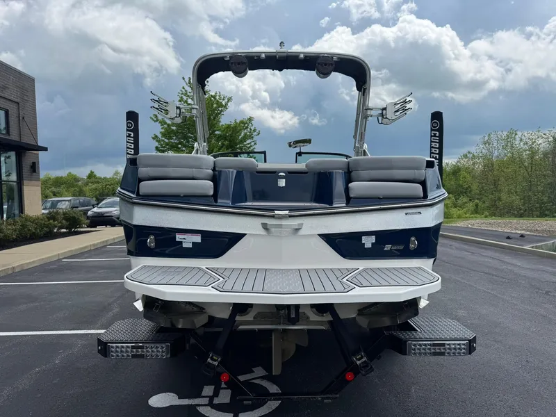 Slide: The Image of 2023 MasterCraft XT23 boat, rear view, parked outdoors under cloudy sky. - 5