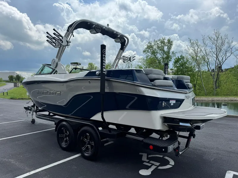 Slide: The Image of 2023 MasterCraft XT23 boat on trailer in parking lot, cloudy sky background. - 6
