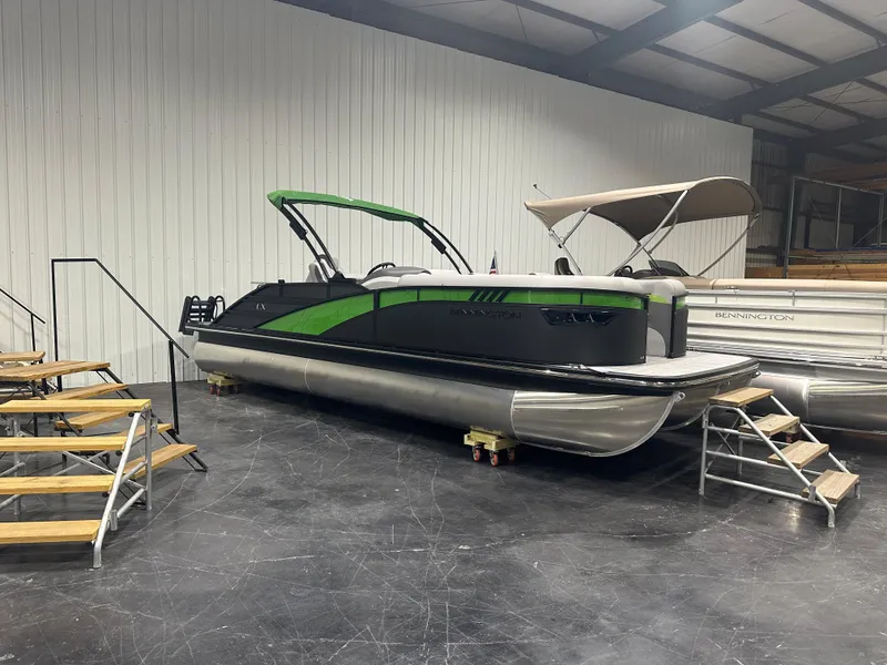 Slide: The Image of 2024 Bennington 24LXS pontoon boat in showroom, green and black design. - 2