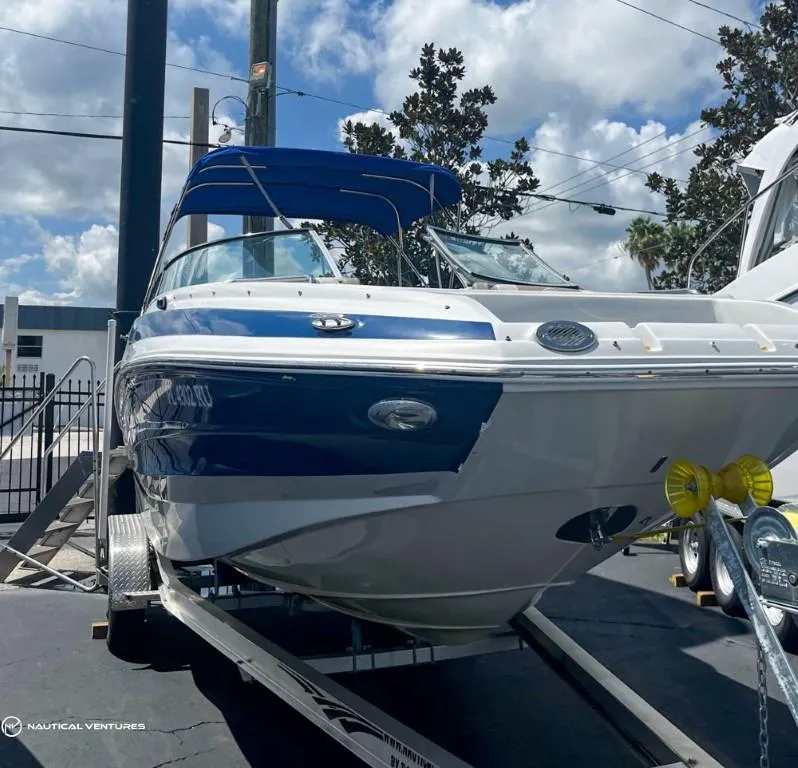 Slide: The Image of 2019 Crownline Eclipse E235 XS boat on a trailer with blue canopy. - 2