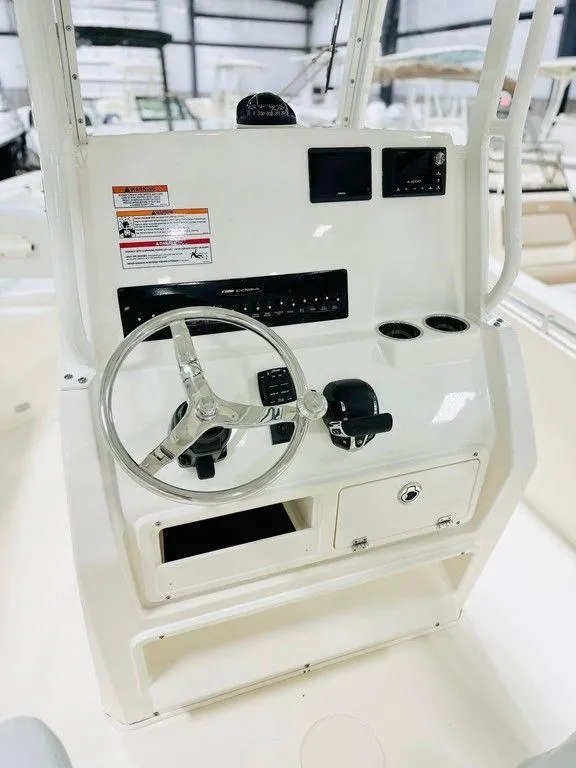 Slide: The Image of 2024 Cobia 240 CC boat console with steering wheel and controls in a showroom. - 18