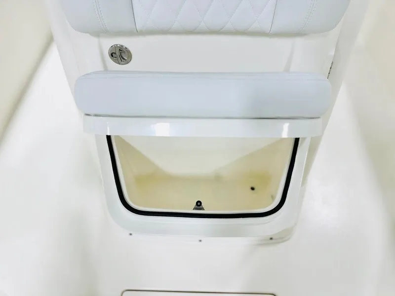 Slide: The Image of 2024 Cobia 240 CC boat storage compartment with white cushioned seat. - 3