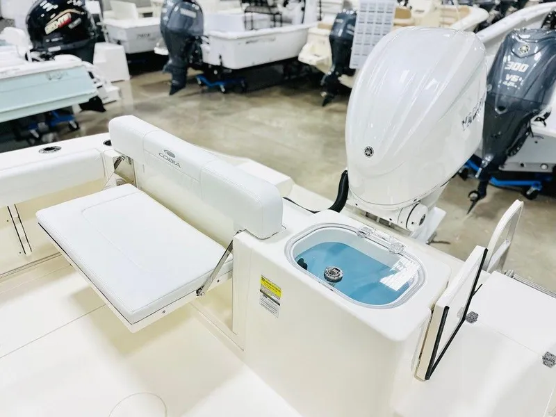 Slide: The Image of 2024 Cobia 240 CC boat interior with seating and motor in showroom. - 5