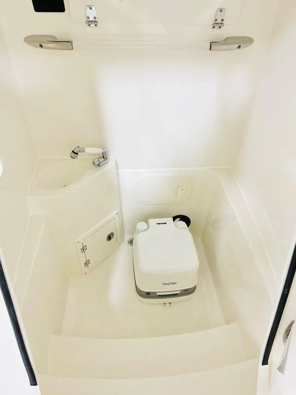 Slide: The Image of 2024 Cobia 240 CC boat interior with compact marine toilet. - 8