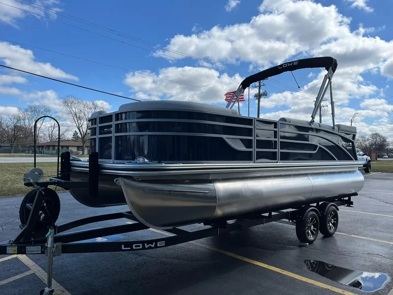 Slide: The Image of 2024 Lowe SS 210 pontoon boat on trailer under a partly cloudy sky. - 3