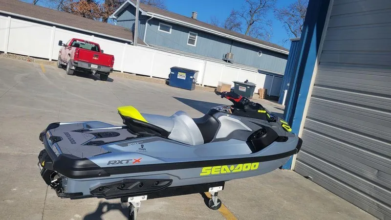 Slide: The Image of 2024 Sea-Doo RXT-X 325 Ice Metal/Manta Green jet ski parked outside. - 4