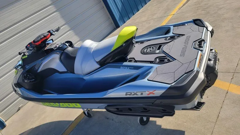 Slide: The Image of 2024 Sea-Doo RXT-X 325 Ice Metal/Manta Green jet ski parked on concrete. - 5