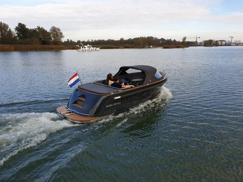 Slide: The Image of 2023 Maxima 620 Retro boat cruising on a serene lake with a Dutch flag. - 14